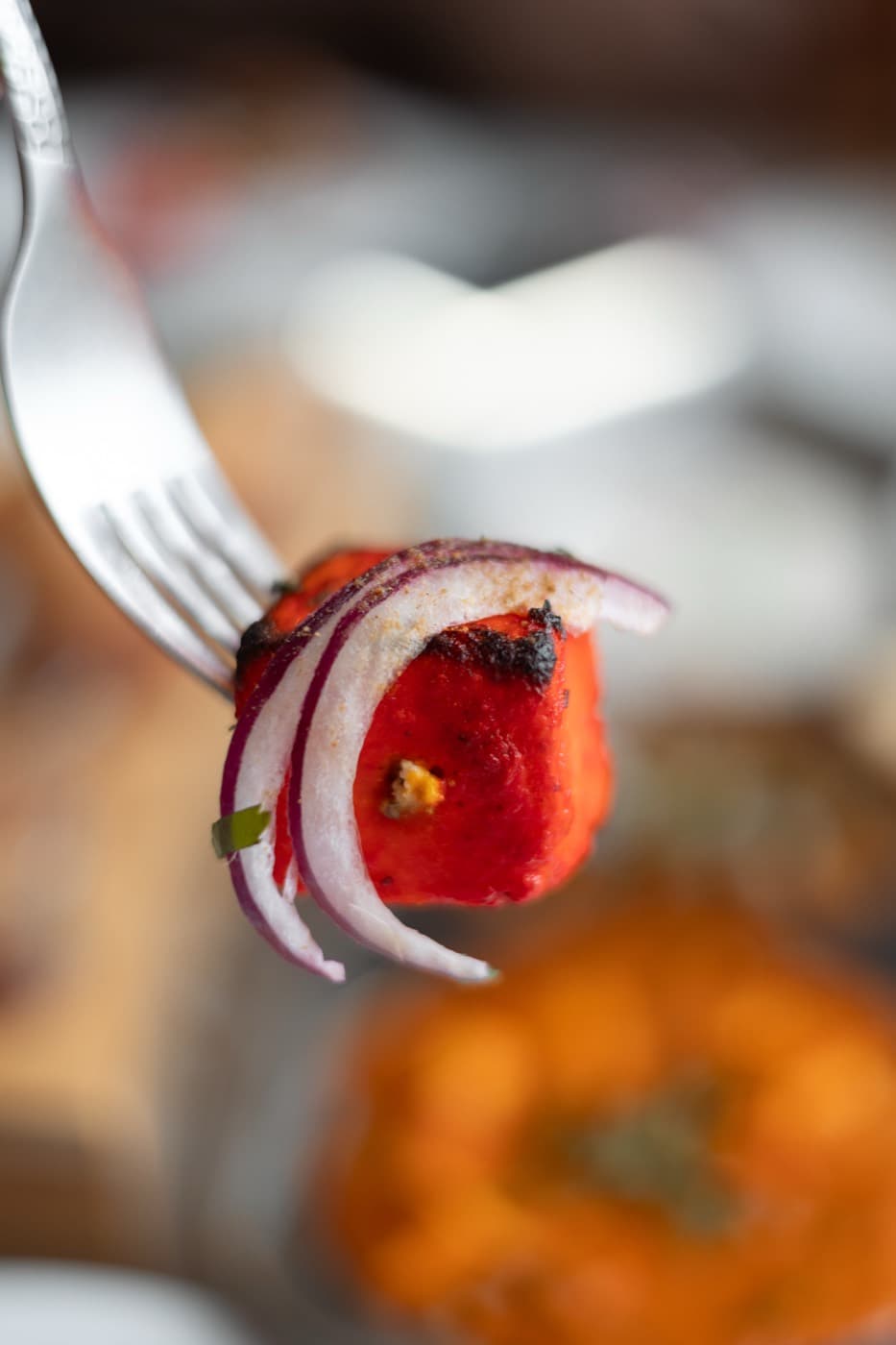 Close-up of tandoori chicken with red onion on a fork at Jewel of India Seattle